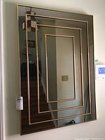 Front angled shot of vintage rectangular mirror showing metal framed geometric inset panels.