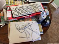 Photo showing white wired keyboard, wired mouse, Canon scanner model F913800 without cord, and two Staples electric pencil sharpeners on a table.