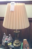 Table lamp with pleated beige shade and brass-style base, lampshade unlit.