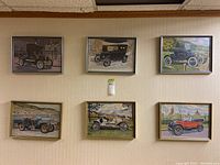 Six vintage car prints behind glass in colored wood frames hanging on wall