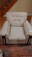 Front view of upholstered arm chair with floral fabric and wood accents on arm sides.