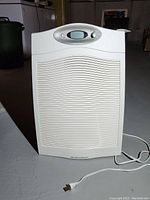 Front view of white Hamilton Beach dehumidifier standing on concrete floor, digital display and controls visible.