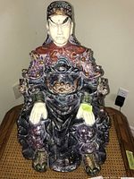 Front view of the figurine showing detailed face, armor and seated posture.