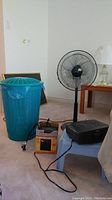 Photo showing all items together: plastic laundry hamper, floor fan, step stool, CD player and heater on carpeted floor with cords visible