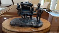 Front angle view of Tudor Mint pewter figurine showing organ grinder man and organ cart on a wooden base.