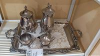Full tea set on ornate silver plated serving tray including teapot, coffee pot, sugar bowl, and creamer.