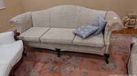 Front view of the three-seat upholstered sofa showing fabric, cushions, and wood legs.