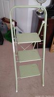Front view of the light green metal step stool with three ribbed steps, showing the structure and height approximately 40 inches.