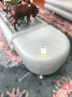 Full view of leather side table with curved edges, light blue-green leather upholstery, and chrome legs.