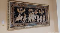 Full view of the framed Burmese Kalaga tapestry showing scene of figures and animals embroidered with sequins on black background.
