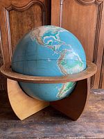 Front view showing the globe centered on the Americas with the wooden circular meridian and tripod wood stand.