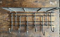 Top view of metal coat rack showing perforated metal top shelf and five hooks with end caps.