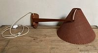 Side view of teak arm and whipstitched fabric shade showing the overall structure and pivoting function.
