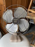 Full front view of the vintage metal fan showing the cage, blades, and base.