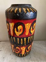 Front view of mid-century modern West German vase showing bold red and yellow swirl patterns with textured lava glaze finish.