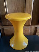 Side angle view of yellow plastic hourglass shaped TamTam Pop stool