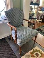 Side angle showing wooden armrest and upholstery pattern with blue-gray fan-shaped motifs.