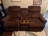 Front view of brown fabric loveseat showing two recliner seats and center console