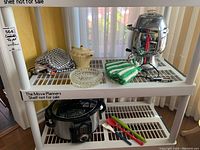 Photo showing electric samovar, Sadler teapot, glass ashtray, cloth bags on a white shelf with window background