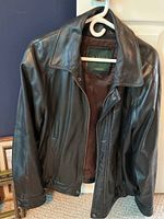 Front view of Danier black leather jacket hanging on hanger, showing zipper and collar.