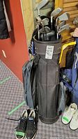 Photo showing black golf bag filled with golf clubs and black golf shoes size 8.5 beside it