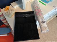 Black Juliette jewelry organizer and rolled floral pattern shelf liner on a white surface, part of other items partially visible.