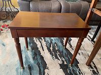 Front view of piano bench showing wood grain top, turned legs, and overall structure.