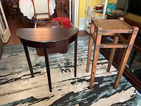 Demi lune painted wood side table and wood wicker-top plant stand side by side on floor