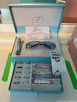 Fondini branded box with instruction sheet, five watch bands, multiple watch bezels, and sunglasses inside.