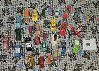 Top view of 30 assorted diecast cars arranged on a patterned surface, showing variety of colors and body styles.