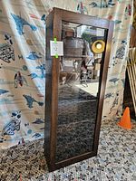 Front view of the closed vintage wooden wall display case with a glass door and wood frame.