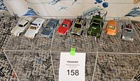 Image showing all 8 diecast cars aligned on a surface with a MaxSold lot sign visible.
