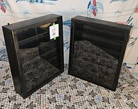 Pair of black wall display cases standing upright showing glass fronts and black frames.