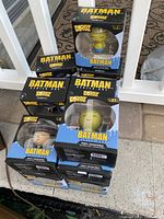 Stack of 16 boxed Batman Dorbz vinyl collectible figures photographed outdoors on a ledge.
