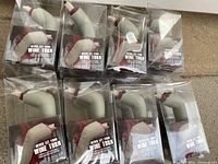 Sixteen individually boxed zombie finger wine stoppers arranged.