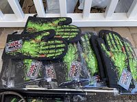 Photo showing multiple zombie hand oven mitts stacked with visible bright green skeletal hand designs and packaging tag