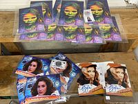 Overview photo of multiple colorful illustrated prints of Addy Miller from The Walking Dead and three signed photo prints of Claudia Wells and P.J. Soles, each in plastic protective sleeves with certificates.
