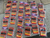 25 Speak & Spell 'Phone Home' fridge magnets arranged on a stone surface, each in their original packaging.