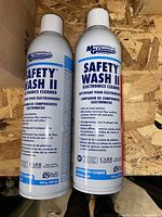 Photo showing two new cans of MG Chemicals Safety-Wash II Electronics Cleaner spray on a wooden surface.