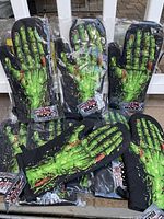 Group of 9 oven mitts with green zombie hand design, still in plastic packaging, tags reading Horror Block exclusive visible.