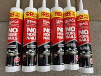 Photo showing six upright tubes of LePage No More Nails construction adhesive with red and black labeled tubes and white applicator tips, highlighting the product and quantity in the lot.
