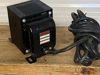 Black Hammond isolation transformer on wooden surface with power cord coiled beside it