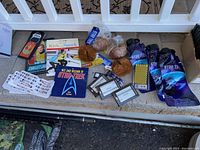 Photo showing various Star Trek collectible items including books, tribbles, trading cards, and bookmarks arranged in a box