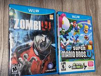 Front covers of Zombie U and New Super Mario Bros. U Wii U games showing game titles and cover art