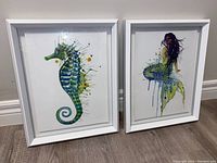 Front view of the two framed wall art pieces showing vibrant seahorse and mermaid designs with white frames.