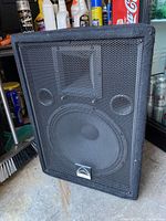 Front and side angled view of black Wharfedale Pro PT-12 loudspeaker with metal mesh grill.