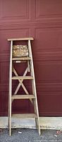 Front view of the 5 foot wooden ladder showing paint stains and the structure leaning against a garage door.