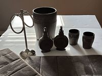 Photo showing the metal hand towel holder, two soap dispensers, two tumblers, wastebasket, and two bath mats.