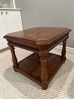 Angled view of the wooden coffee table showing top scratches and turned leg design.