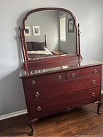 Front view of dresser and attached mirror with glass top protector in bedroom setting